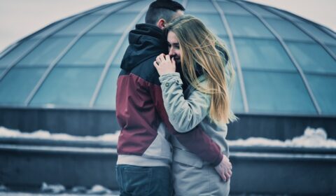 Pareja joven abrazándose al aire libre en un entorno urbano durante el invierno, representando la conexión emocional en una relación de pareja.